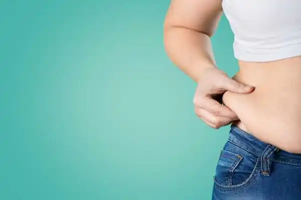 Image of woman pinching her love handles to show weight gain Maplehurst