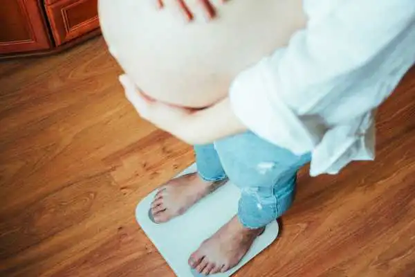 Image of woman weighing herself and experiencing weight gain through pregnancy Maplehurst